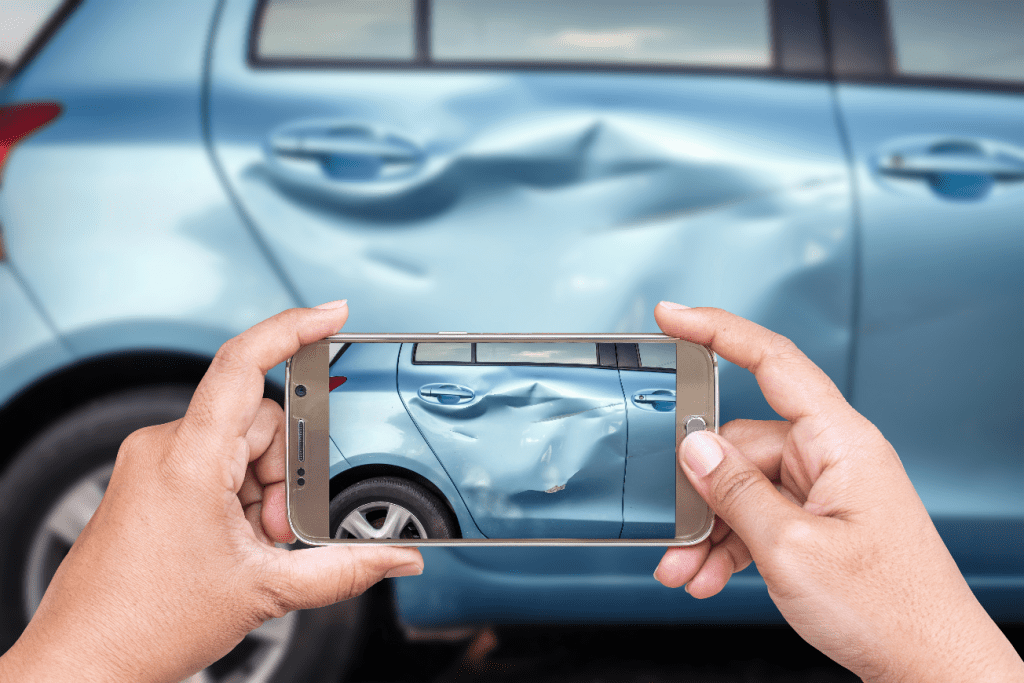 man taking a photo of a dent in his blue car