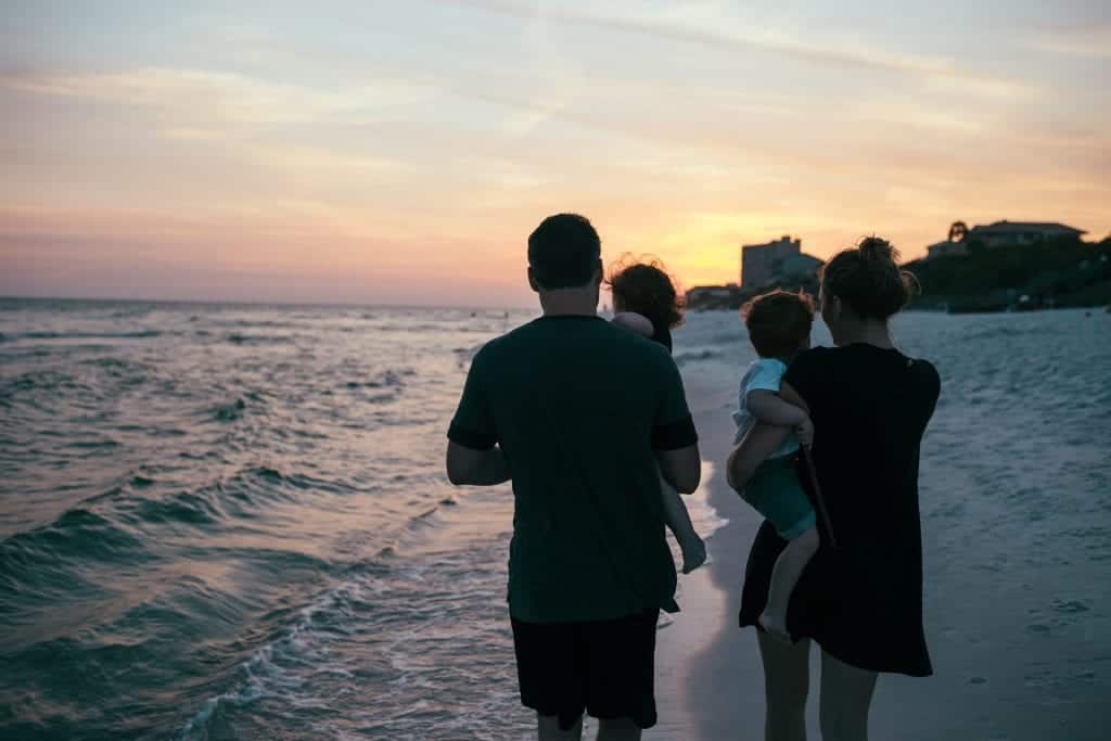 Young couple with children walking on the beach