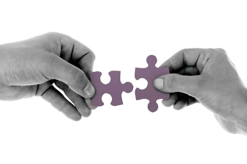 two hands holding a jigsaw piece close together