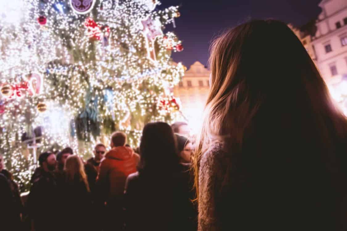 brown haired woman standing in front of a Christmas tree