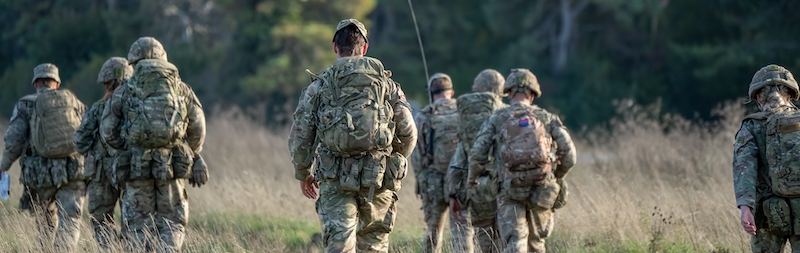 8 male and female British army soldiers tabbing with 25Kg bergens across open countryside, Wiltshire UK